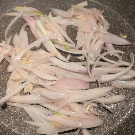 Sliced onion and garlic softening in olive oil at the start of kapunata