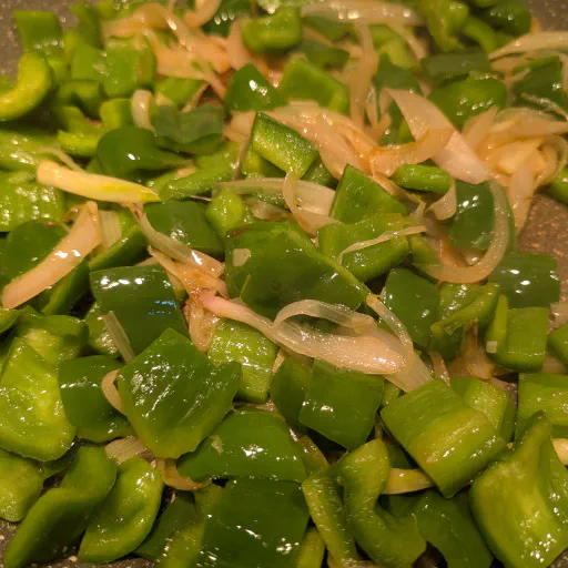 Green pepper slices cooking with softened onion and garlic